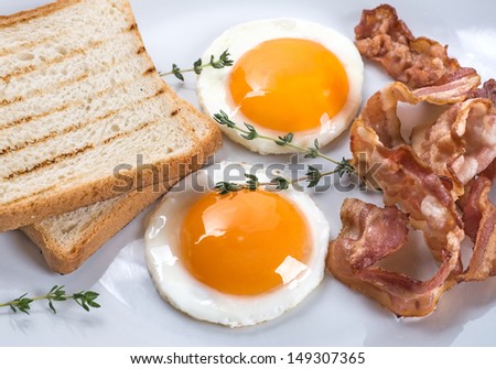 Close-up of fried eggs, bacon and toasts