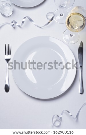 Table set with a single plate and white wine - background for menu