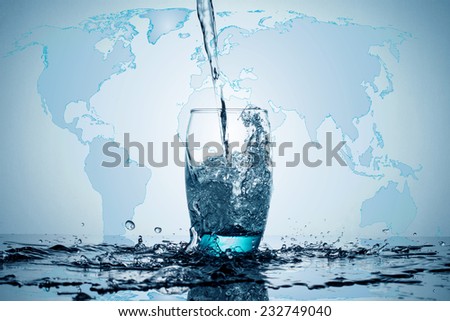 Water flowing and splashing into a glass with world map