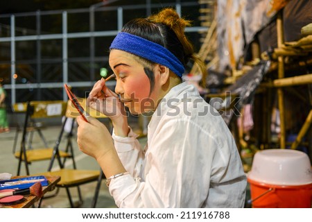 Hong Kong, China - August 18, 2014: A traditional opera actor is making up at the back stage of a traditional tea house. Generally, an actor needs 30 - 60 minutes to complete the whole process.