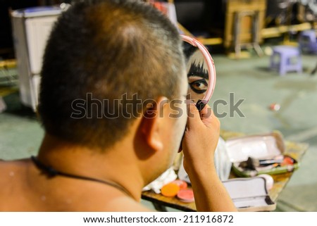 Hong Kong, China - August 18, 2014: A traditional opera actor is making up at the back stage of a traditional tea house. Generally, an actor needs 30 - 60 minutes to complete the whole process.