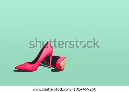 Red high heels isolated on a bright green pastel background. Fashion concept, catwalk. A modern and fashionable shoe store.