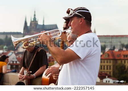 Prague, Czech Republic - 15th September, 2014: Trumpet player of jazz band plays on Charles bridge with view on Prague castle and Saint Vitus cathedral in background.  Charle\'s bridge is popular place