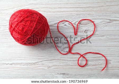 red ball of wool on wooden table background