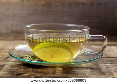 The cup of green tea with tea leaves and lemon