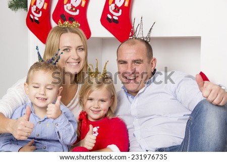 family sitting near a Christmas tree and Christmas fireplace and laughs