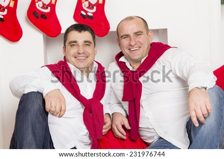 Two friends sitting near the Christmas fireplace and laugh