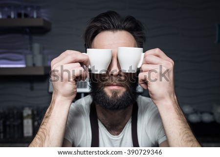 bartender keeps cups of coffee near face; bearded man wants to wake up in morning;