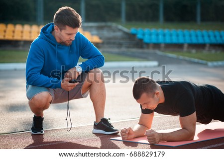 fitness outdoor workout with trainer; morning plank exercises with personal coach with stopwatch;