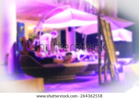 outdoor restaurant in the neon light. Visitors can relax under the parasols. Blurred background
