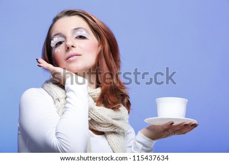 Beautiful winter young woman portrait with white eye-lashes eyelash hat violet and drink tea cup