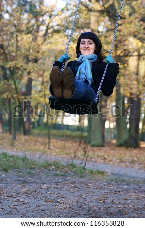 woman in blue scarf swing on a swing autumn park