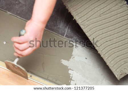 Man Construction worker is tiling at home, tile floor adhesive