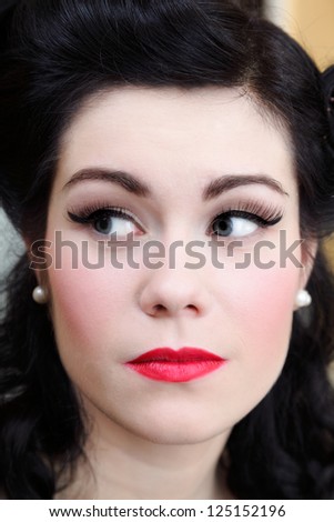 Beautiful young woman with pin-up make-up and hairstyle posing indoor