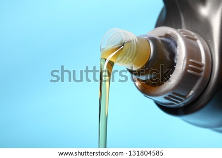 Can with car engine oil pouring in front  blue background