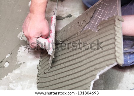 Man Construction worker is tiling at home, tile floor adhesive