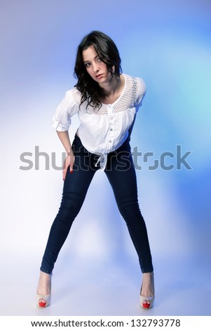 Portrait of stylish young plus size woman in fashion jeans high heels on blue background.