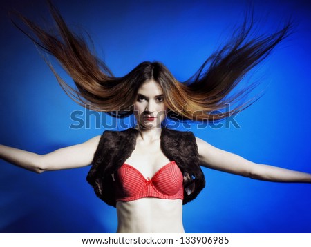 Fashion model with hair blowing in the wind blue background