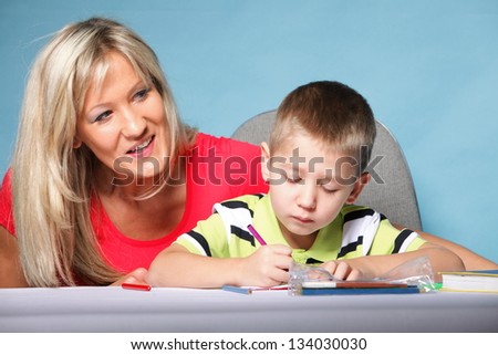 mother and son drawing together, mom helping with homework blue background