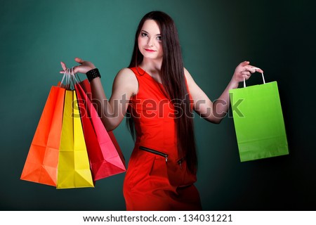 young woman long hair with paper multi coloured shopping bags on green background. Sales and discounts concept.