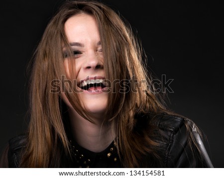 Beautiful happy laughing woman in rock style on black background