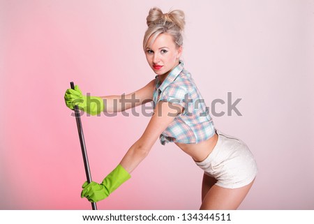 Cheerful pin up girl retro style portrait pinup Woman housewife cleaner mop pink background