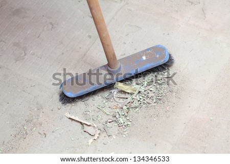 rough concrete at a job site using a large blue broom