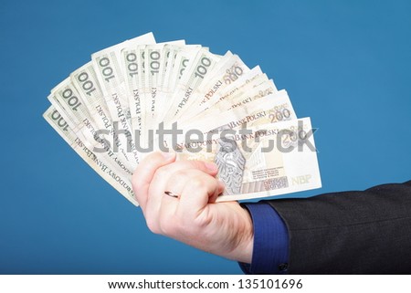 Businessman\'s hand holding polish money banknote blue background