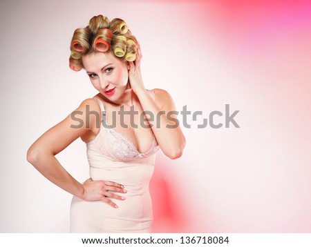 Sexy blonde woman preparing to party, girl in underwear with curlers in hair pink background