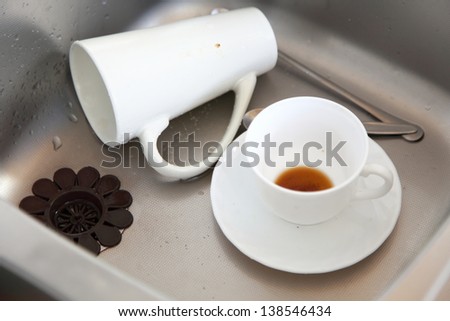 Washing up. White coffee cups in the kitchen sink.
