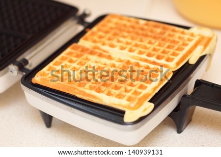 Waffle iron in the kitchen. Preparing homemade waffles.