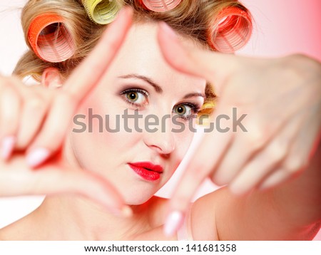 Sexy woman preparing to party, girl in underwear curlers in hair having fun, making frame with hands, taking picture with imaginary camera pink background