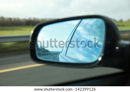 Rear view on a car mirror reflecting road