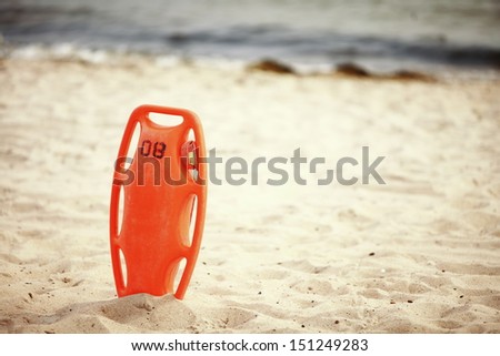 Beach life-saving. Lifeguard rescue equipment orange preserver tool, red plastic buoyancy aid in the sand