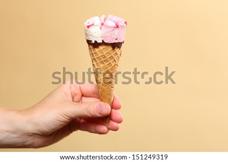 Berry icecream waffle cone in hand on orange. Refreshing dessert for summertime.
