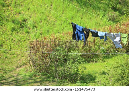 clothes hanging to dry on a laundry line against green hill