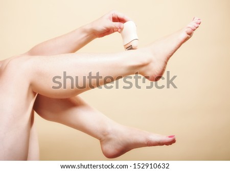 woman shaving her legs with electric shaver depilation on orange. Beauty and skin body care concept.