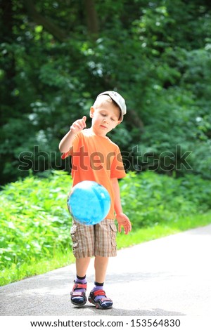 Boy in action young kid playing with ball in park outdoors. Healthy leisure time
