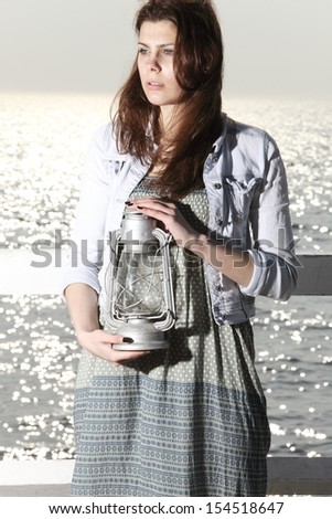 young woman on pier with a oil kerosene lamp. Concept carrying light, daylight
