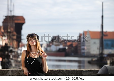 Flapper girl. Retro styled fashion portrait of vintage woman from roaring 1920s outdoor. Old town Gdansk in the background