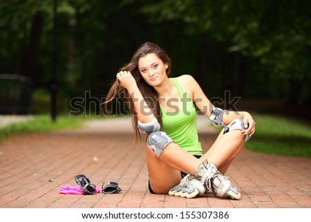 Happy young girl enjoying roller skating rollerblading on inline skates sport in park. Woman in outdoor activities
