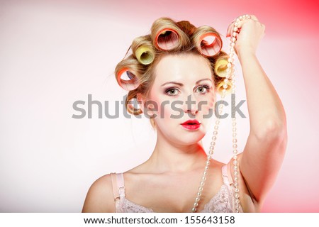 Sexy woman preparing to party, girl in underwear curlers in hair with beads pink background