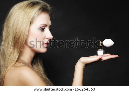 Sensuality concept. Portrait beautiful woman with perfume bottle on black background