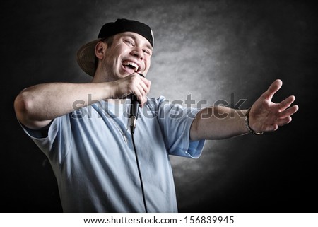 Rapper attitude rap singer hip Hop Dancer performing. Young man with microphone singing hand cool gesture black grunge background