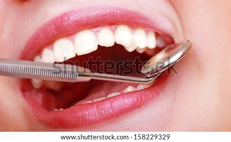 Dental care. Close-up young female having her teeth examinated. Healthy woman teeth and dentist mouth mirror.