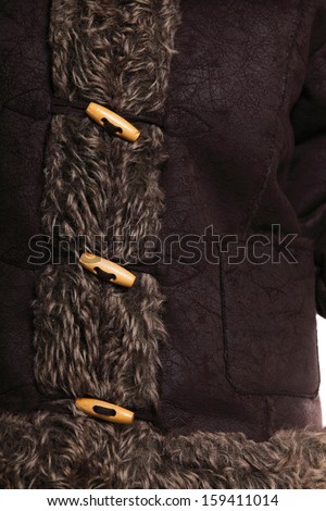 winter fashion warm clothing part of fur jacket with wooden button as wear background