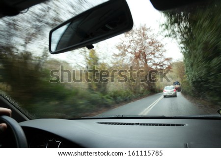 Driver\'s hand on a steering wheel of a car and road