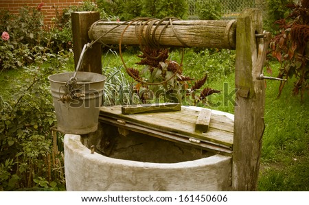 old rotten water well in summer garden, rural scenery