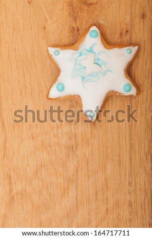 Christmas. Homemade gingerbread cake star with icing and blue decoration on wooden board. Holiday handmade concept.