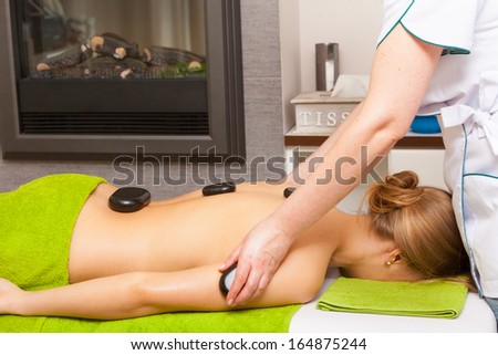 Beauty treatment concept. Woman relaxing getting spa hot stone therapy back massage procedure in salon. Body care healthy lifestyle.